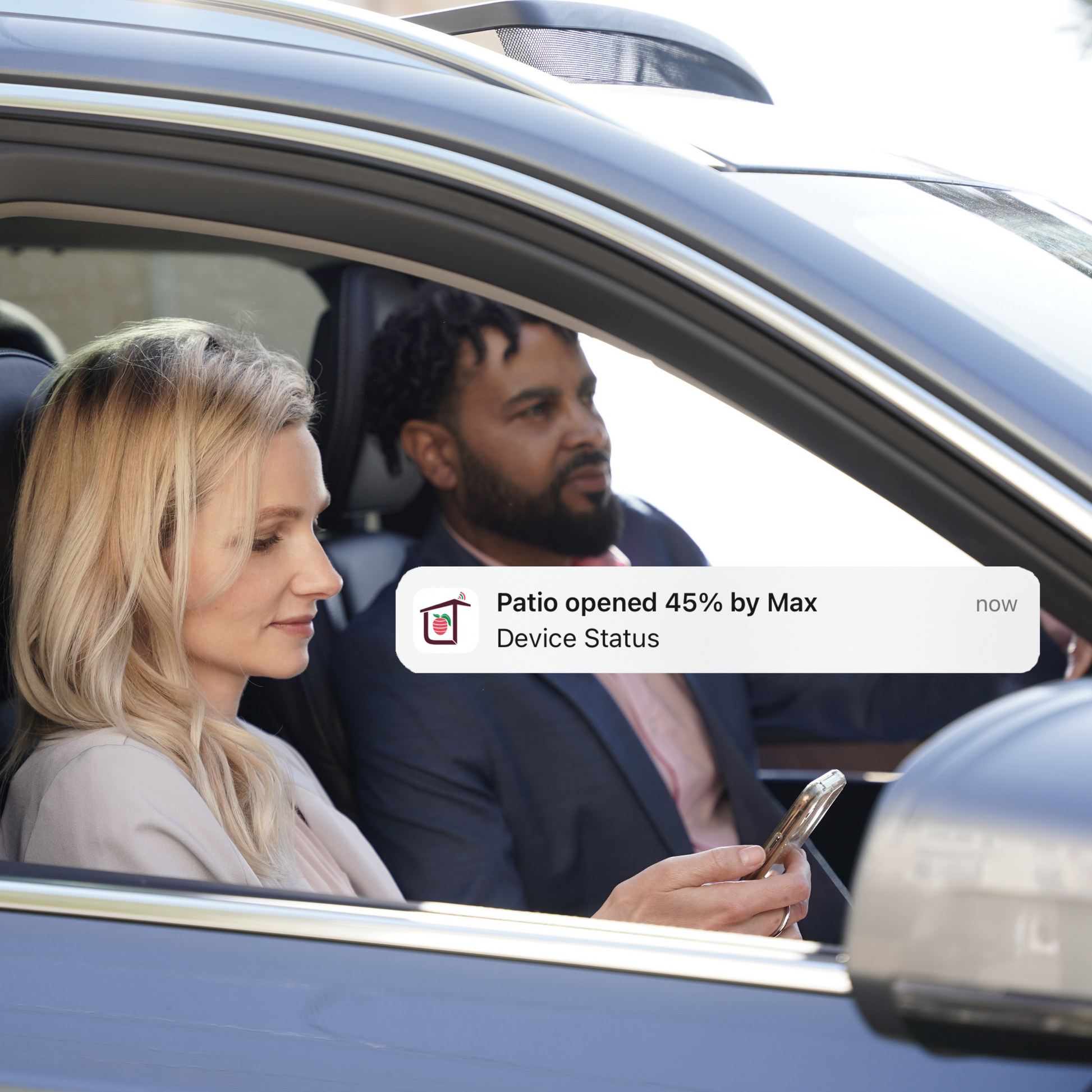 Image of a couple in a car receiving a real-time mobile notification, showing their dog has opened the patio door using its SmartSlydr PetPass tag, highlighting remote monitoring and peace of mind.